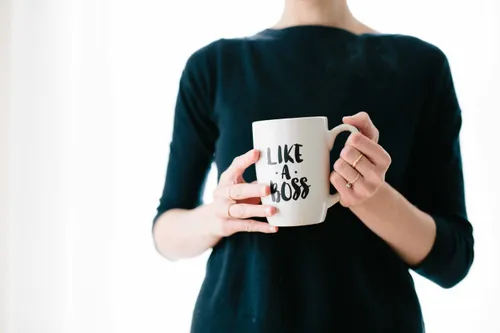 Woman in black holding a coffee mug that says “Like A Boss”