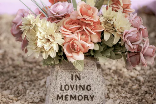 Gravestone with flowers that says “In Loving Memory”.