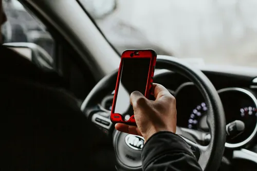 Person looking at their mobile phone while in the driver's seat.